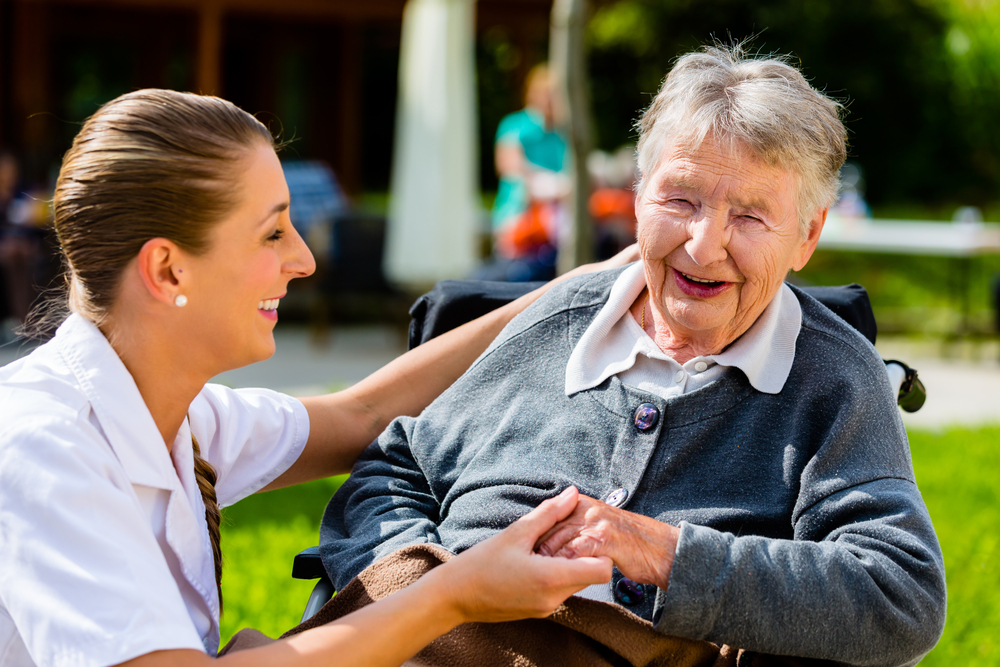 alzheimer: casa di riposo o badante? Un infermiera di una casa di risposo fa sorridere un'anziana