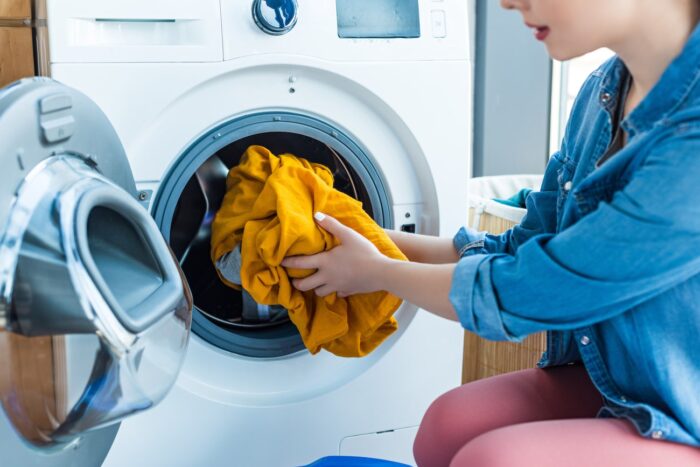 inquadramento colf e badante: donna che mette i panni in lavatrice