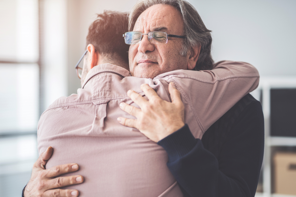 anziano rifiuta assistenza badante: padre e figlio in un abbraccio