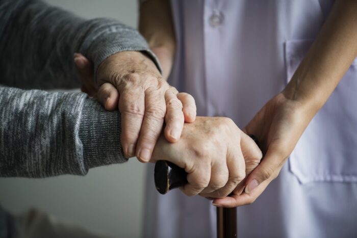 festività badante: badante che sorregge le mani di un'anziana assistita